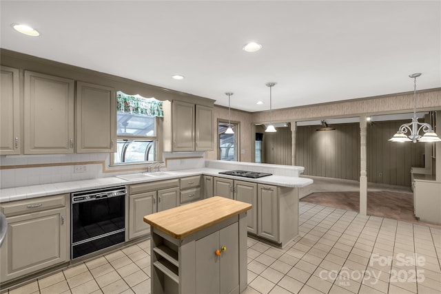 kitchen with gray cabinets, a center island, decorative light fixtures, and black appliances