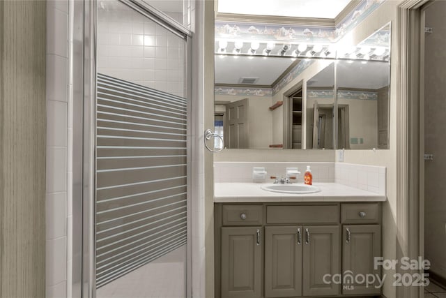 bathroom with crown molding, vanity, a shower with shower door, and tasteful backsplash