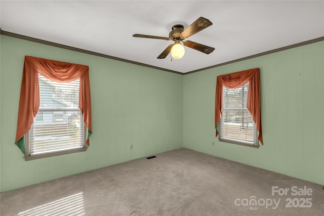 spare room featuring crown molding, light colored carpet, and ceiling fan