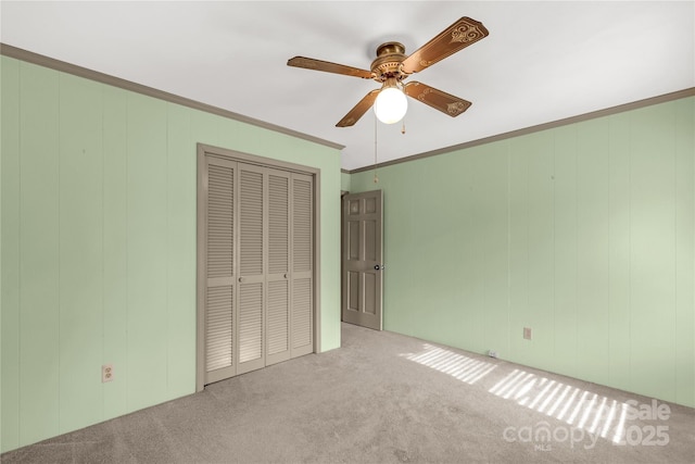 unfurnished bedroom with crown molding, a closet, ceiling fan, and light carpet