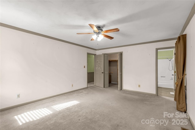 unfurnished bedroom featuring connected bathroom, light colored carpet, ornamental molding, and ceiling fan