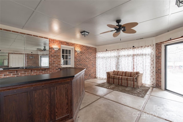 interior space featuring brick wall, dark brown cabinets, and ceiling fan