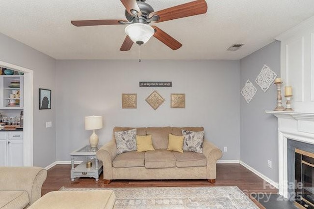 living room with ceiling fan, dark wood-type flooring, and a textured ceiling