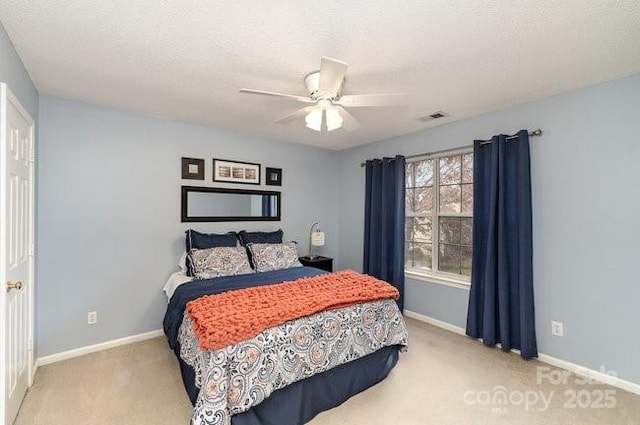 bedroom featuring ceiling fan, light colored carpet, and a textured ceiling