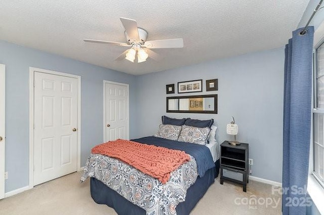 bedroom with ceiling fan, light colored carpet, and a textured ceiling