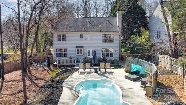 rear view of house with a fenced in pool, a fenced backyard, a chimney, and a patio area