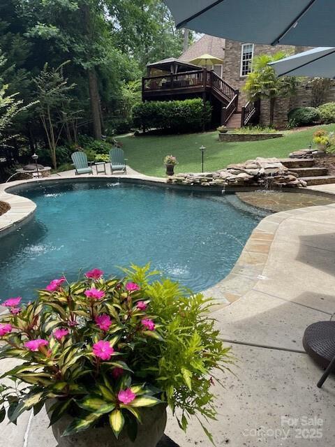 view of pool with a yard, a patio area, and a wooden deck