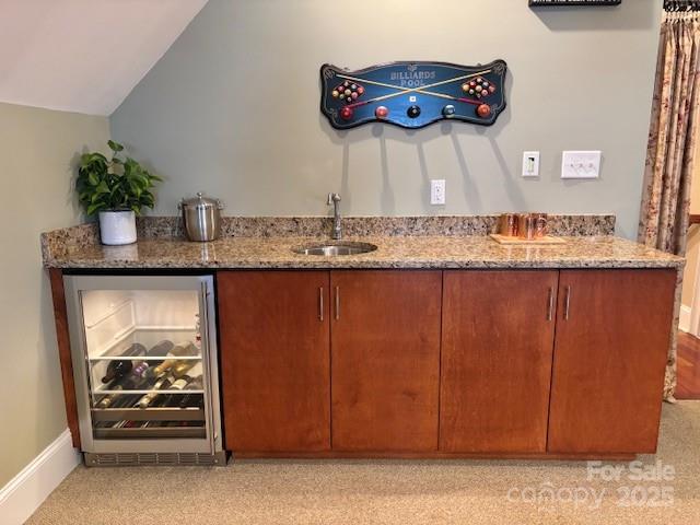 bar featuring light stone counters, sink, lofted ceiling, and wine cooler