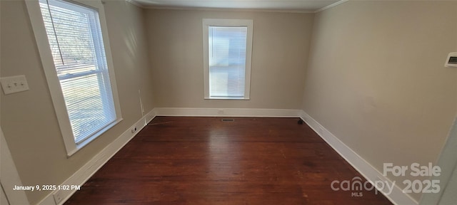 empty room featuring dark wood-type flooring and ornamental molding