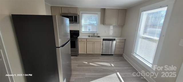 kitchen with appliances with stainless steel finishes, light hardwood / wood-style floors, tasteful backsplash, and sink