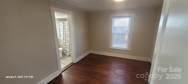 spare room featuring dark wood-type flooring and crown molding