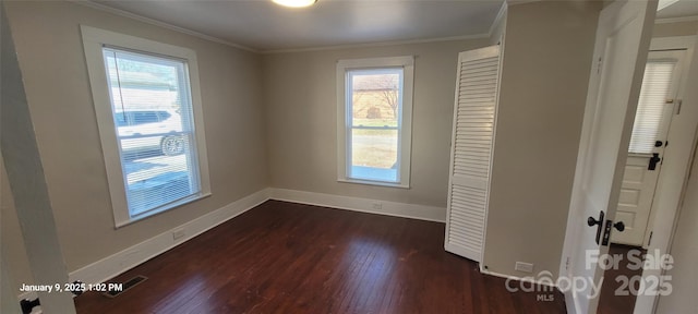 empty room with dark wood-type flooring, crown molding, and plenty of natural light