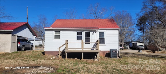 rear view of property with cooling unit, a carport, and a yard