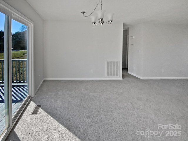 spare room featuring an inviting chandelier and carpet floors