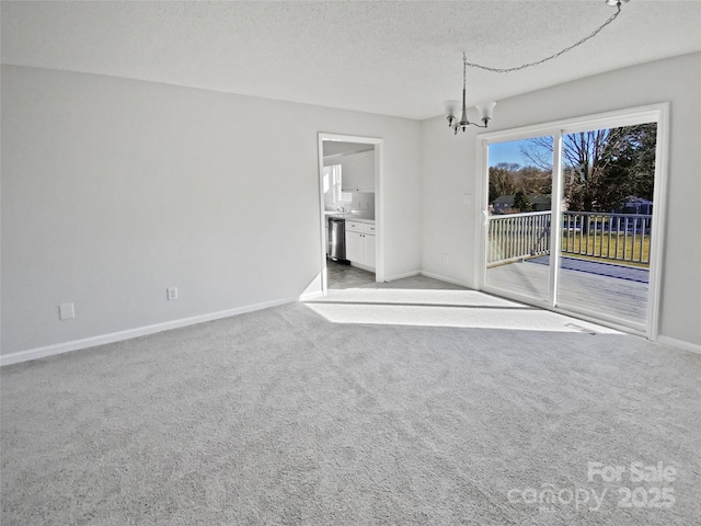 carpeted empty room with a textured ceiling and a chandelier