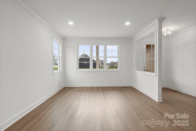 empty room with plenty of natural light, wood finished floors, and ornamental molding