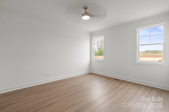 unfurnished room featuring light wood-style floors, a ceiling fan, baseboards, and ornamental molding