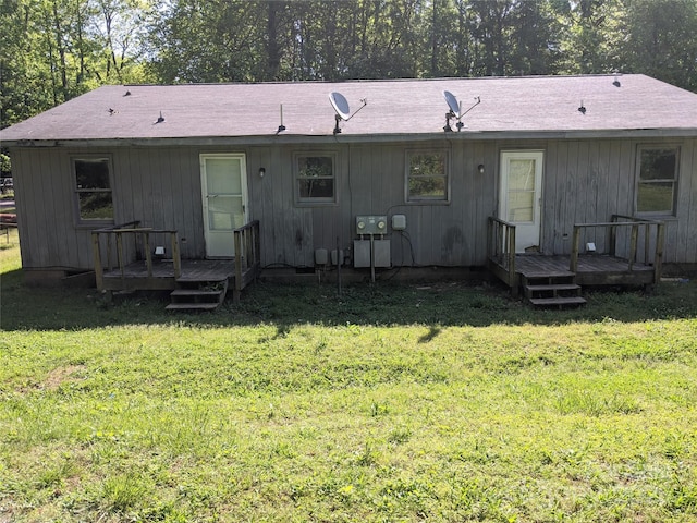 back of property with a deck and a yard