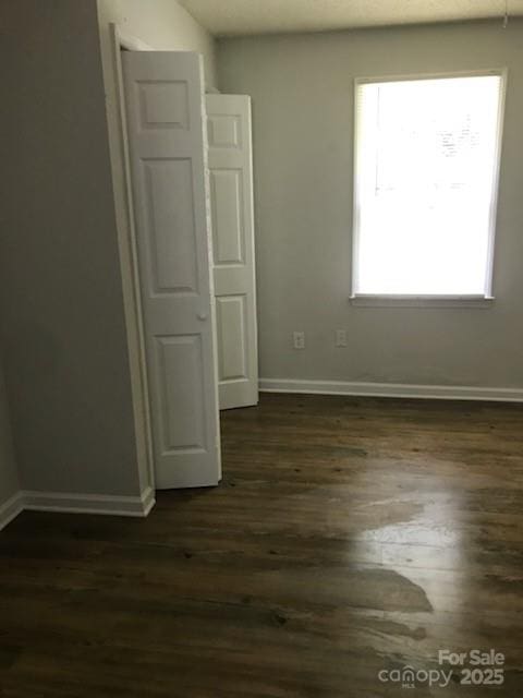 unfurnished room featuring a wealth of natural light and dark hardwood / wood-style floors