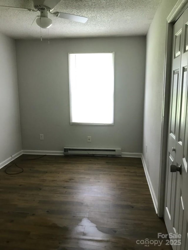 empty room featuring ceiling fan, a baseboard radiator, a textured ceiling, and dark hardwood / wood-style floors