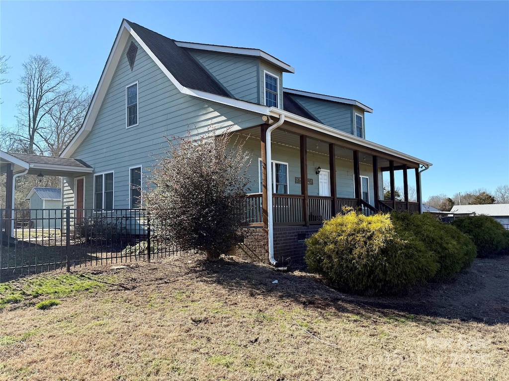 view of side of property with a porch and a yard