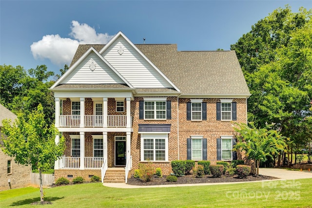 view of front facade featuring a balcony, a front lawn, and covered porch