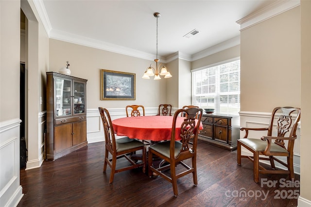 dining area with dark wood-type flooring, a chandelier, and ornamental molding