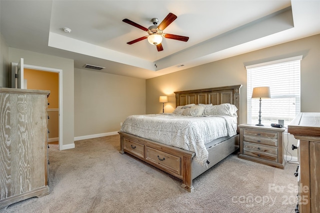 carpeted bedroom featuring a raised ceiling and ceiling fan