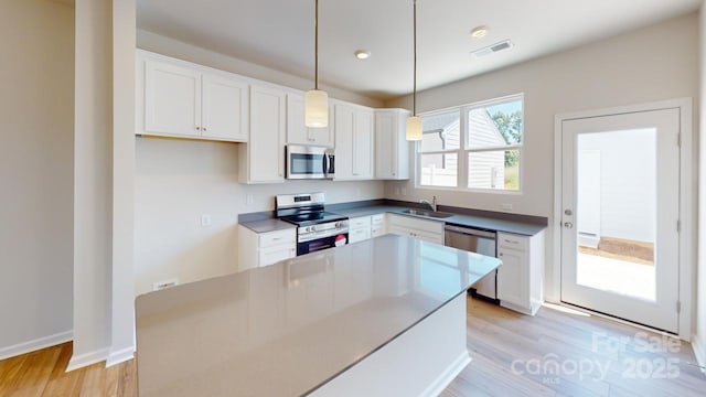 kitchen featuring white cabinets, pendant lighting, and appliances with stainless steel finishes