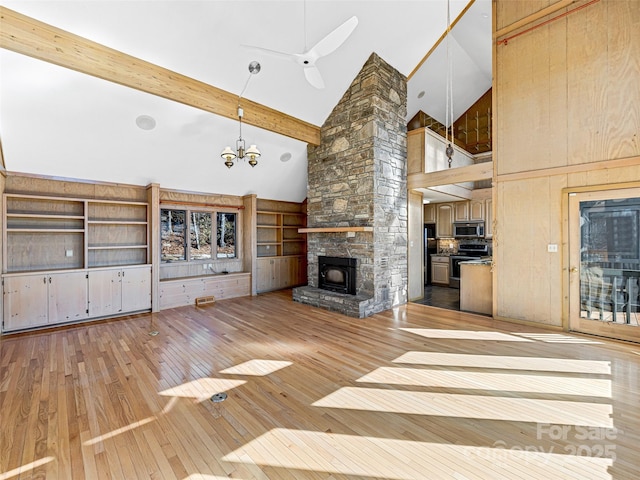 unfurnished living room featuring a stone fireplace, high vaulted ceiling, beamed ceiling, light hardwood / wood-style floors, and an inviting chandelier