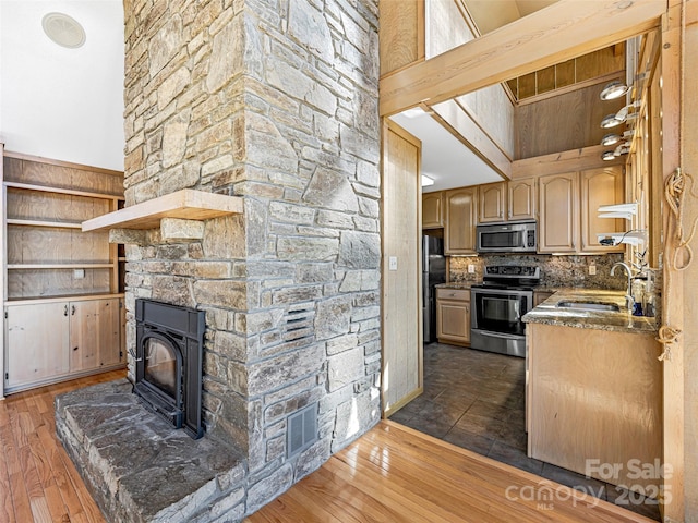 kitchen featuring appliances with stainless steel finishes, light brown cabinetry, sink, a high ceiling, and dark wood-type flooring