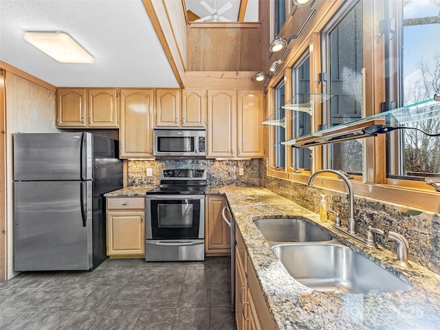 kitchen featuring sink, appliances with stainless steel finishes, backsplash, light stone countertops, and light brown cabinetry