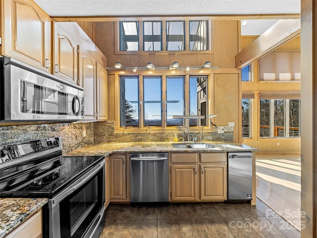 kitchen with light stone countertops, wood walls, and appliances with stainless steel finishes