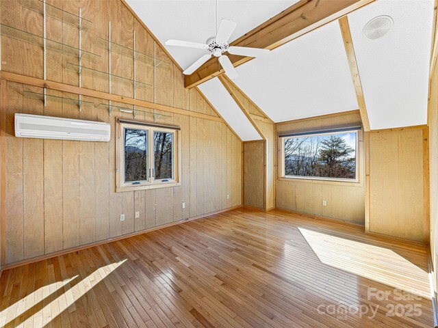 additional living space with vaulted ceiling with beams, wooden walls, an AC wall unit, and wood-type flooring