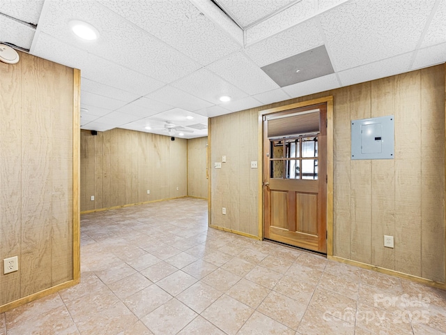 interior space featuring a paneled ceiling, wooden walls, and electric panel