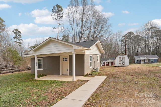 view of front of home featuring a front yard, a patio, and a storage unit