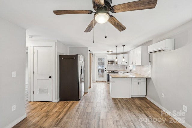 kitchen with stainless steel appliances, a wall mounted air conditioner, white cabinets, and kitchen peninsula