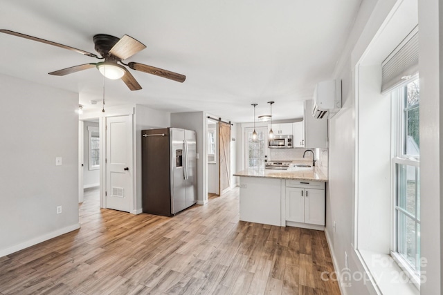 kitchen with sink, white cabinets, stainless steel appliances, a barn door, and backsplash