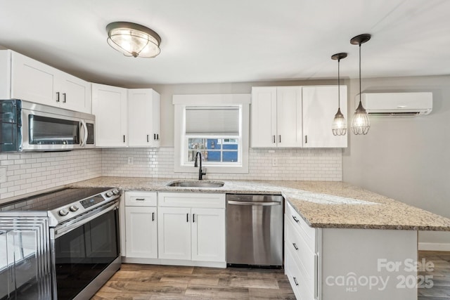 kitchen featuring sink, a wall mounted AC, kitchen peninsula, stainless steel appliances, and white cabinets