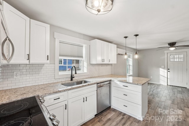 kitchen with white cabinetry, sink, stainless steel appliances, and kitchen peninsula