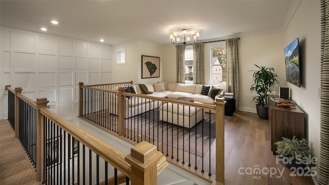 living area featuring an upstairs landing, an inviting chandelier, crown molding, and wood finished floors