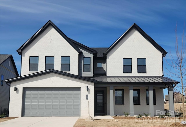 modern farmhouse featuring brick siding, a porch, concrete driveway, a standing seam roof, and a garage