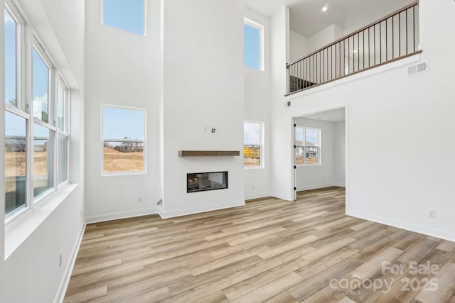604 Hyder Trl, Tega Cay, SC 29708 - unfurnished living room featuring a high ceiling, wood finished floors, a glass covered fireplace, and baseboards