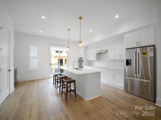 2534 Weddington Ave Unit 11, Charlotte, NC 28204 - kitchen featuring appliances with stainless steel finishes, an island with sink, white cabinetry, under cabinet range hood, and light wood-type flooring