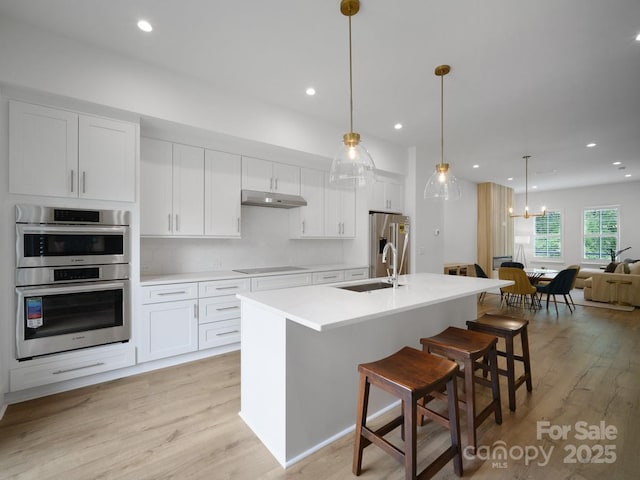 2530 Weddington Ave Unit 12, Charlotte, NC 28204 - kitchen with under cabinet range hood, stainless steel appliances, white cabinets, a breakfast bar area, and recessed lighting