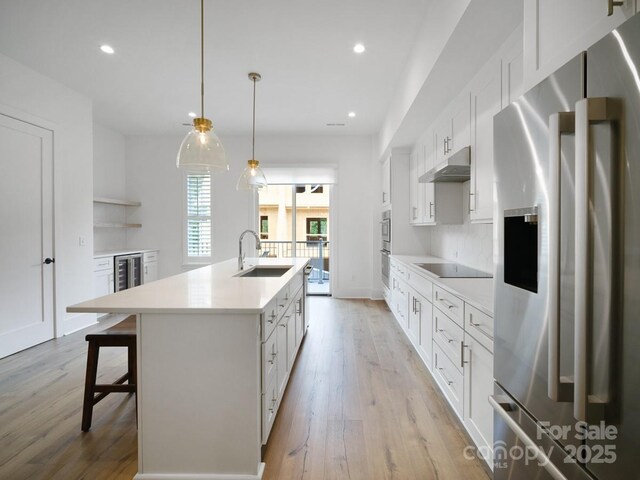2530 Weddington Ave Unit 12, Charlotte, NC 28204 - kitchen featuring appliances with stainless steel finishes, a sink, a kitchen island with sink, under cabinet range hood, and light wood-type flooring