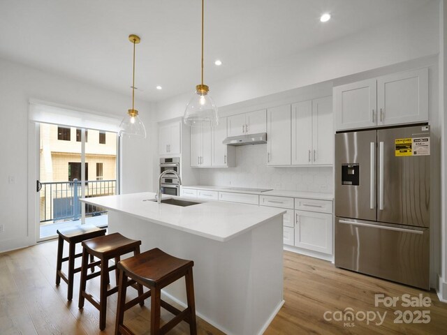 2530 Weddington Ave Unit 12, Charlotte, NC 28204 - kitchen featuring appliances with stainless steel finishes, light wood-type flooring, white cabinets, a center island with sink, and a sink