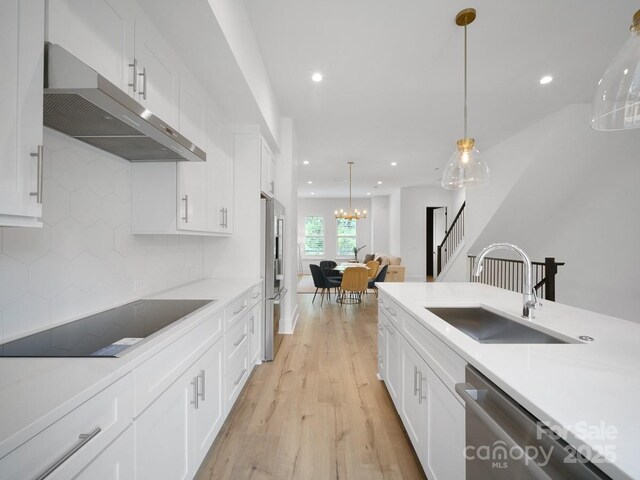 2530 Weddington Ave Unit 12, Charlotte, NC 28204 - kitchen featuring under cabinet range hood, a sink, stainless steel appliances, light wood-style floors, and white cabinetry