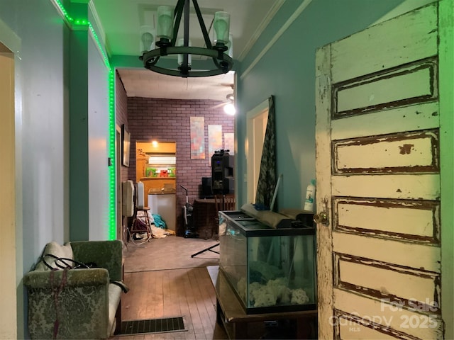 interior space featuring crown molding, brick wall, and hardwood / wood-style floors