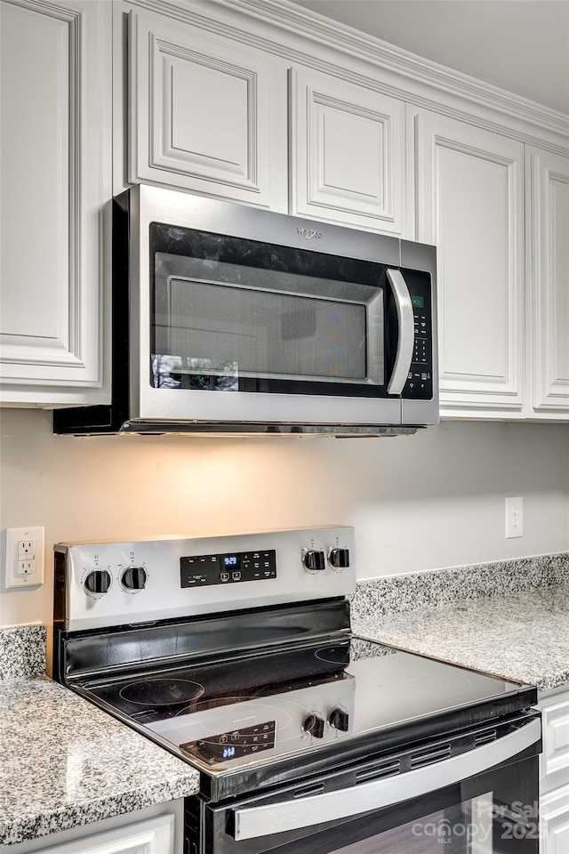 kitchen with appliances with stainless steel finishes, white cabinets, and light stone countertops